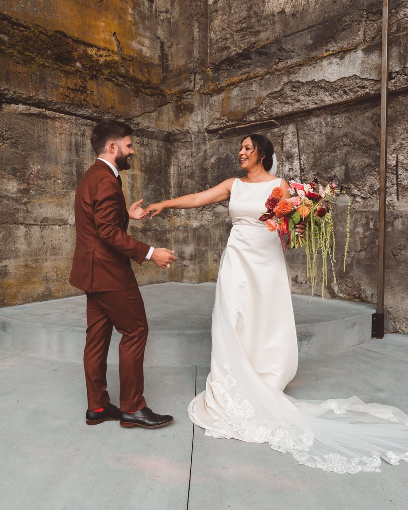 A candid wedding portrait of the bride and groom dancing and laughing.